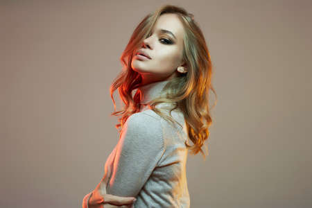 Beautiful young woman in red light. sensual beautiful girl with make-up and curly blond Hairの写真素材