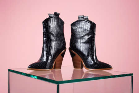 Trendy Women's boots. fashion still life. female black boots on glass. demi-season shoes
