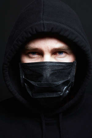Man in Mask and Hood. Boy in Black Mask and Hoodie.の写真素材
