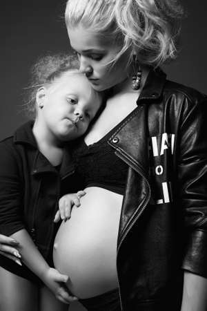beautiful pregnant woman with child. beauty stylish Mother and daughter. Happy Family. young mother woman with child baby girl. Black and white portraitの写真素材