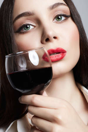 beautiful Girl with glass of wine. Beautiful woman drinking red wine. Red lips Make-upの写真素材