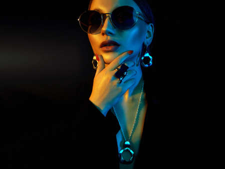 beauty girl in color bright lights. Fashion portrait of beautiful girl in sunglasses and jewelryの写真素材