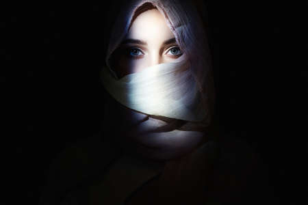 beautiful young woman in hijab, looking from the dark. beauty girl in hood. fashion oriental womanの写真素材