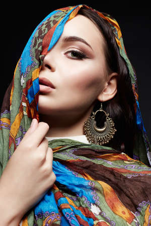 beautiful young woman in color veil and jewelry. beauty girl in colorful hijab. fashion oriental womanの写真素材