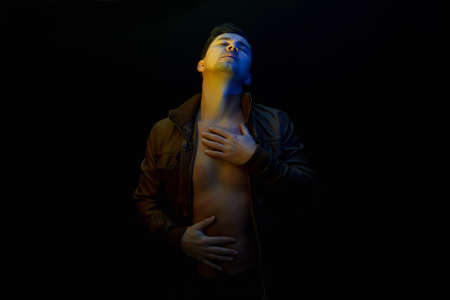 young Man. sexy Handsome Boy in color lights. Male model posing in black studioの写真素材