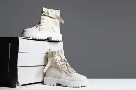 white boots on a wooden box. fashion shoes still life. stylish photo in the studio