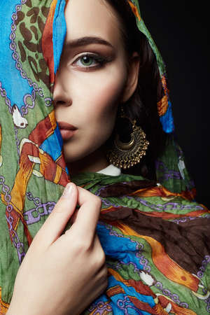 closeup portrait of beautiful young woman in color veil and jewelry. fashion oriental style girl in colorful hijabの写真素材
