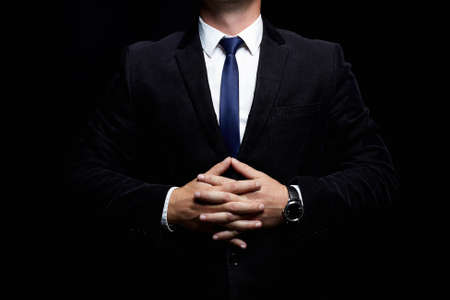 stylish Buisnessman in a suit and tie holding his hands in the lock. Leadership