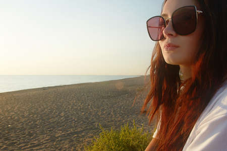 Lifestyle portrait of happy lovely girl in sunglasses on the beach