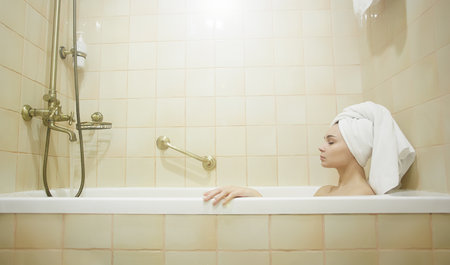 Portrait of young woman relaxing in bathtub. Beautiful girl in towel