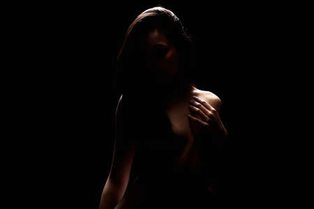 Nude Woman silhouette under light in the dark. Beautiful Sexy Naked Body Girlの写真素材