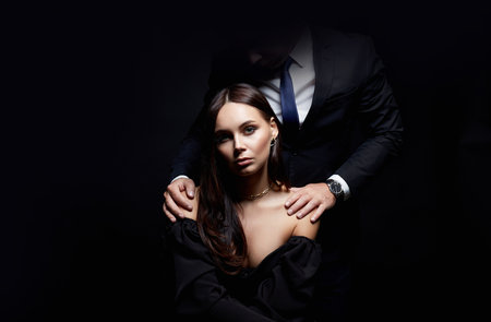 beautiful woman with man dark. Couple over black background. Adorable, elegant girl seducing her handsome boyfriendの写真素材