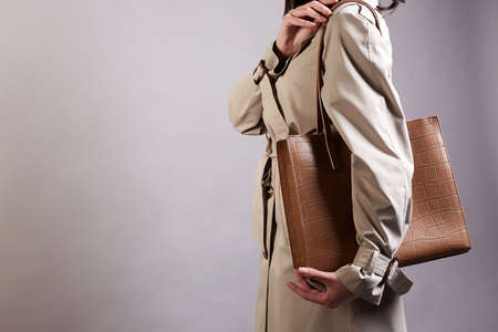 young woman in trendy trench coat and bag. Fashionable girl holding Handbagの写真素材