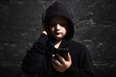little boy in black hoodie and headphones. portrait of teenager boy listening music by phone. Childの写真素材