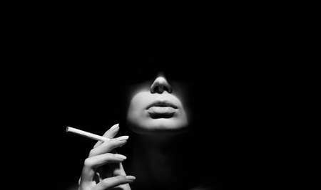 Beautiful woman with a cigarette in the dark. Black and white portraitの写真素材