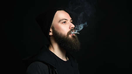 handsome bearded smoking man in Hat. Hipster boy with cigaretteの写真素材