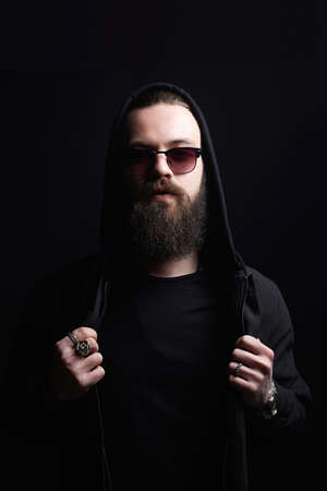 Man in Hood and sunglasses. Boy in a hoodie. portrait of bearded man in the dark