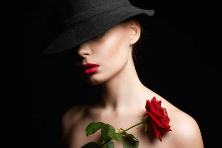 Beautiful young Woman In Hat and Flower. Lovely girl with make-up and Red Rose. beauty portraitの写真素材