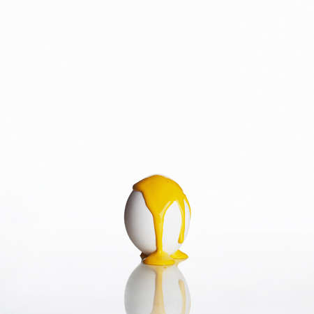 Easter egg isolated on a white background. Yellow paint runs down the egg. minimalist poster