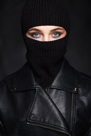 beautiful girl in black balaclava and leather coat. Trendy Mask on pretty woman. new hat styleの写真素材