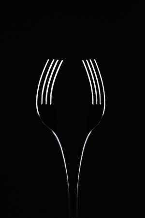 pair of forks on black background look like a wine glass. abstract minimalist composition. art...
