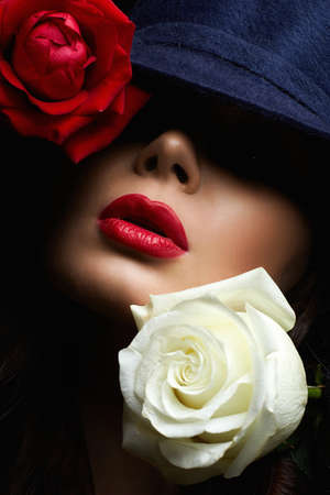Beautiful young Woman In Hat and Flowers. Lovely girl with make-up and Two Roses. beauty portraitの写真素材