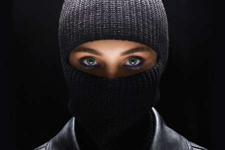 Fashionable girl in black balaclava and leather coat. Beautiful female eyes under Maskの写真素材