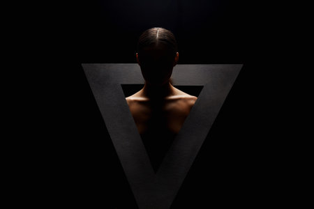naked woman in triangle. art portrait of nude girl in the dark. silhouetteの写真素材