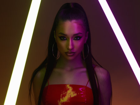 beautiful young woman with neon lamp. Dancer girl in latex. studio portraitの写真素材