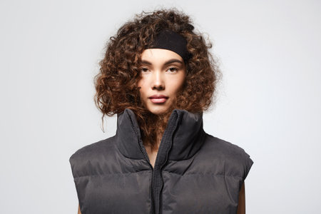 fashion portrait of beautiful young woman in stylish vest. pretty curly hairstyle girlの写真素材