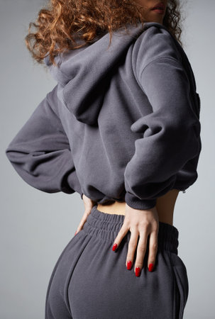 fashion portrait of beautiful young curled woman in hoodie. pretty curly hairstyle girl