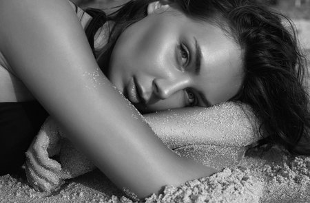 Beautiful young woman in sand on beach. pretty girl in Bikini sunbathing at the resort