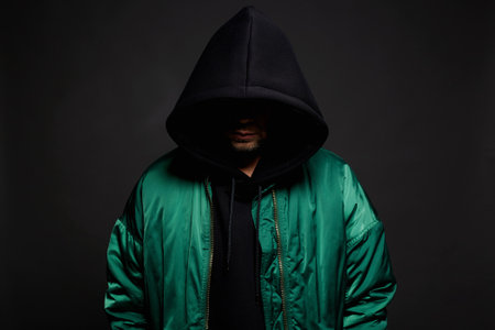 Stylish Man in Black Hood and green bomber jacket. Trendy wear Boy in a hooded sweatshirt