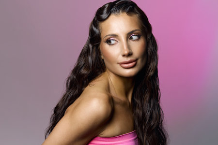 beautiful happy woman with wet curly hair style and make-up. tanned skin pretty girl over pink backgroundの写真素材