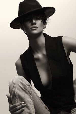 Monochrome portrait of Young Sexy Woman in hat. Beautiful stylish Girl in vest on naked bodyの写真素材