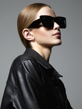 Beautiful young woman in sunglasses and leather coat. stylish blond girl in black glassesの写真素材