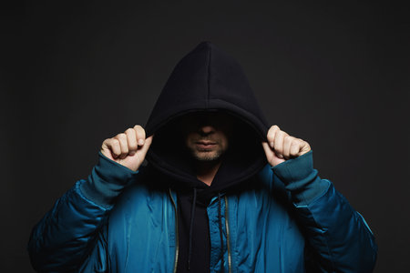 Stylish Man. Person in Black Hood and bomber jacket. Trendy wear Boy in a hooded sweatshirt