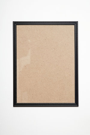 black picture frame on white wall. Stylish photoframe for poster or picture. Blank frame background