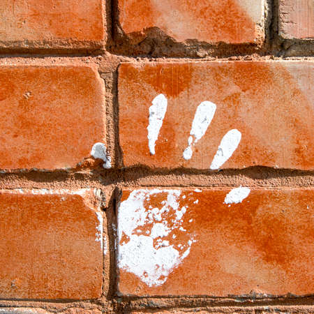 White paint print of right hand on red brick wallの写真素材