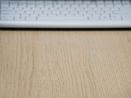 Wooden surface office table with blurred white keyboard with copy space.の写真素材
