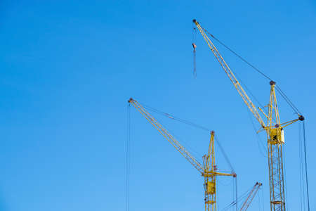 The yellow cranes at the construction site against the blue sky