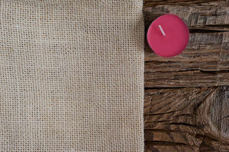 Seasonâs greeting card design concept with copy space. Beige cloth, a mulberry purple candle on a coarse wood background.の写真素材