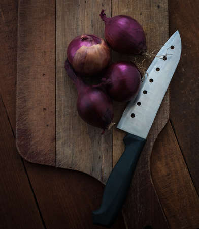 Food preparation, cooking concept: fresh raw red onions, knife on a rustic wooden cutting board backgroundの写真素材