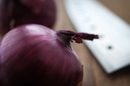 Food preparation, cooking concept: fresh raw red onions, knife on a rustic wooden cutting board backgroundの写真素材