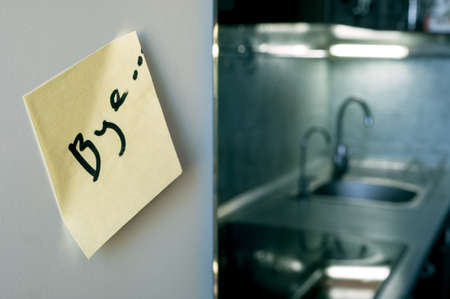 End of relationship concept: a goodbye note on a refrigerator with kitchen appliances and cold lights in blurred backgroundの写真素材