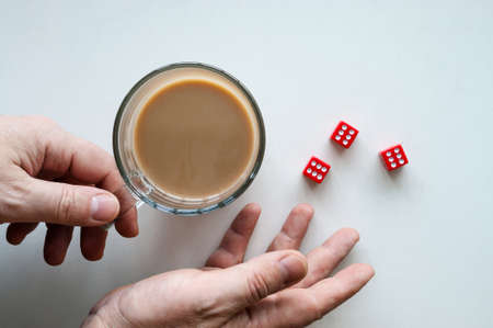 Hands rolling red dice six seals, a glass mug of coffee,  isolated background, top view.の写真素材