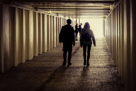 A couple of teenagers walks in the underpass with a group of girls staying at the entrance
