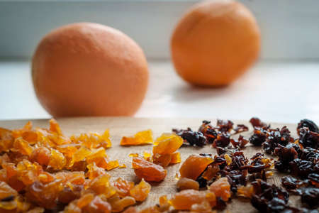 Healthy Diet Food Ingredients: Chopped Dried Apricots And Prunes On A Wooden Cutting Board. Oranges In The Background.の写真素材