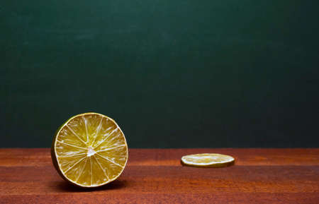 Cross Section Of A Lime And A Lime Slice On A Wooden Table. Green Background. Organic Accent To The Flavors Of Foods And Beverages.の写真素材