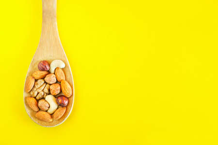 Assorted Nuts In A Wooden Spoon On Yellow Background. Healthy Organic Snack, Breakfast, Food...